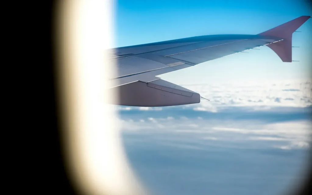 Airplane wing above the clouds seen through a cabin window
