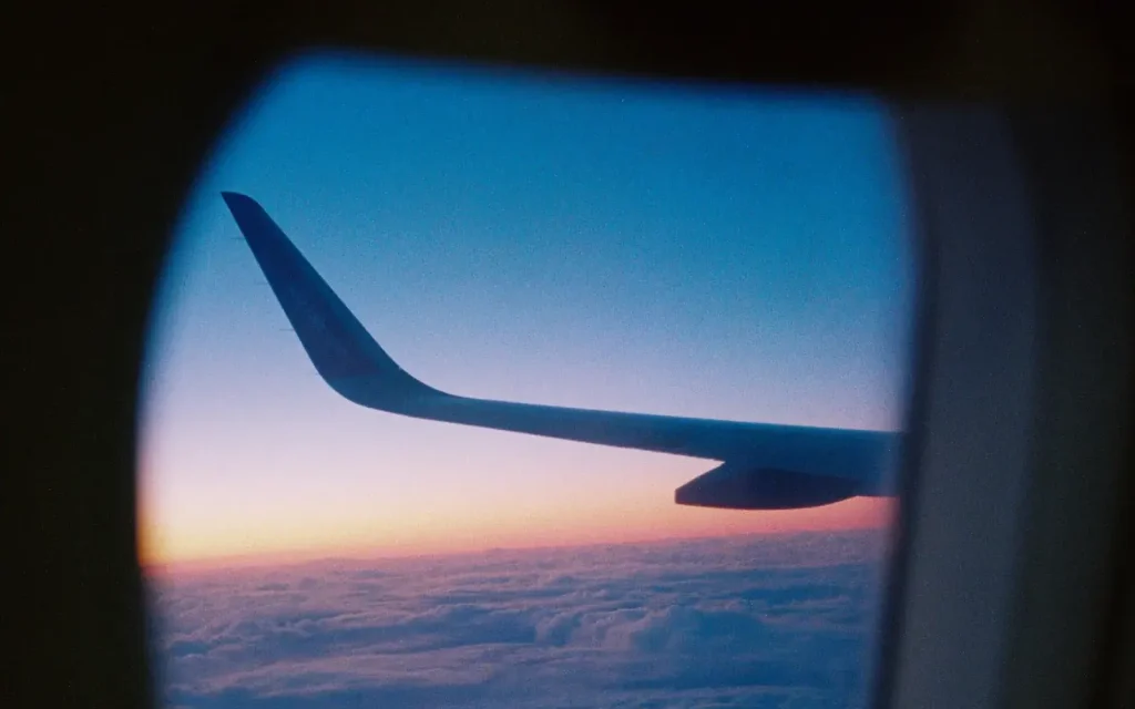 Airplane wing at sunset, seen through a cabin window