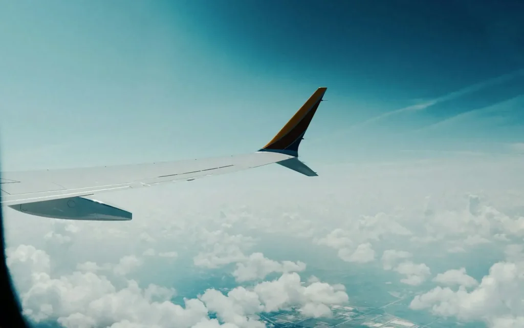 Airplane wing over the clouds through a cabin window