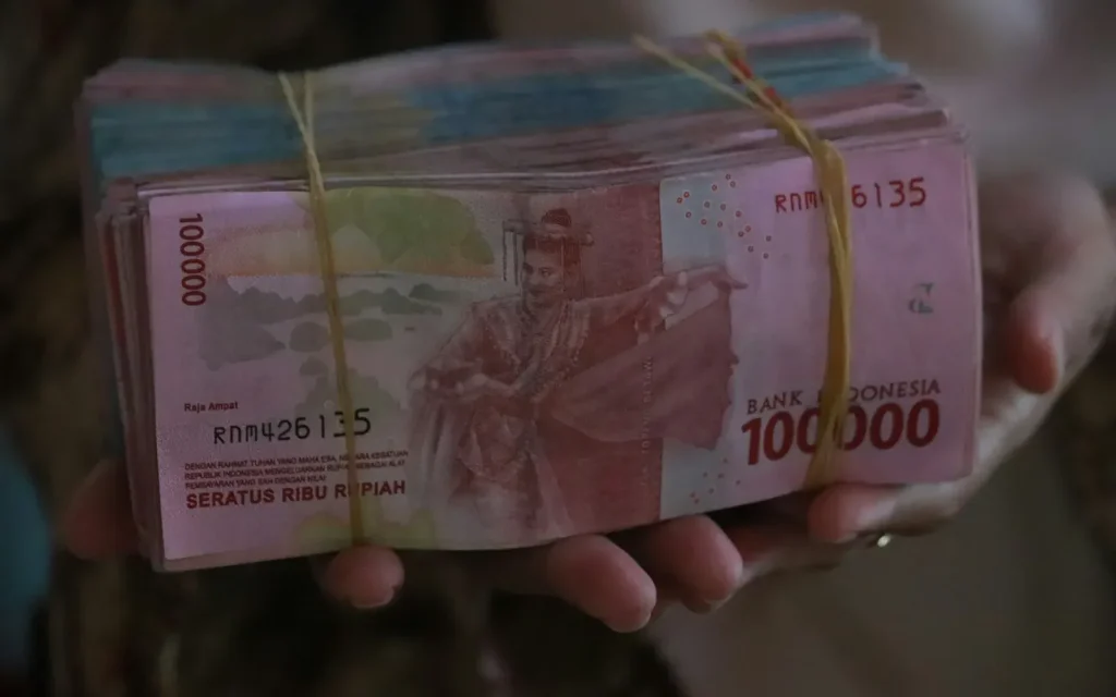 Hand holding a bundle of Indonesian rupiah banknotes