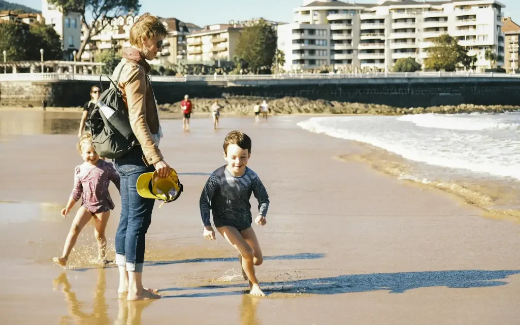 Parent and two children walking along the shoreline