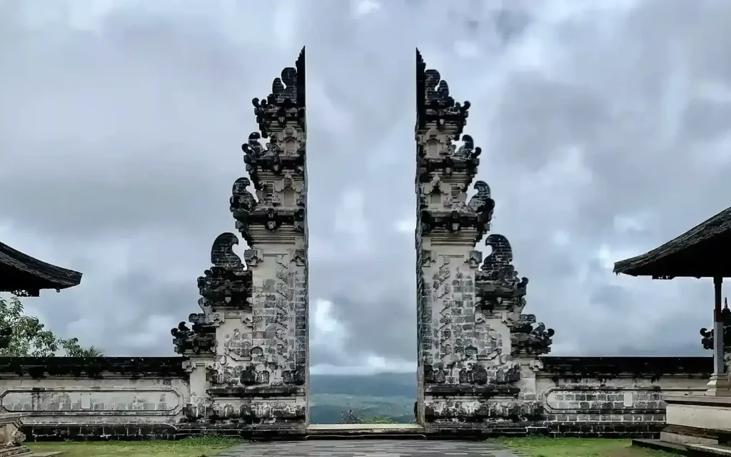 Split gate of a Balinese hillside temple under a cloudy sky