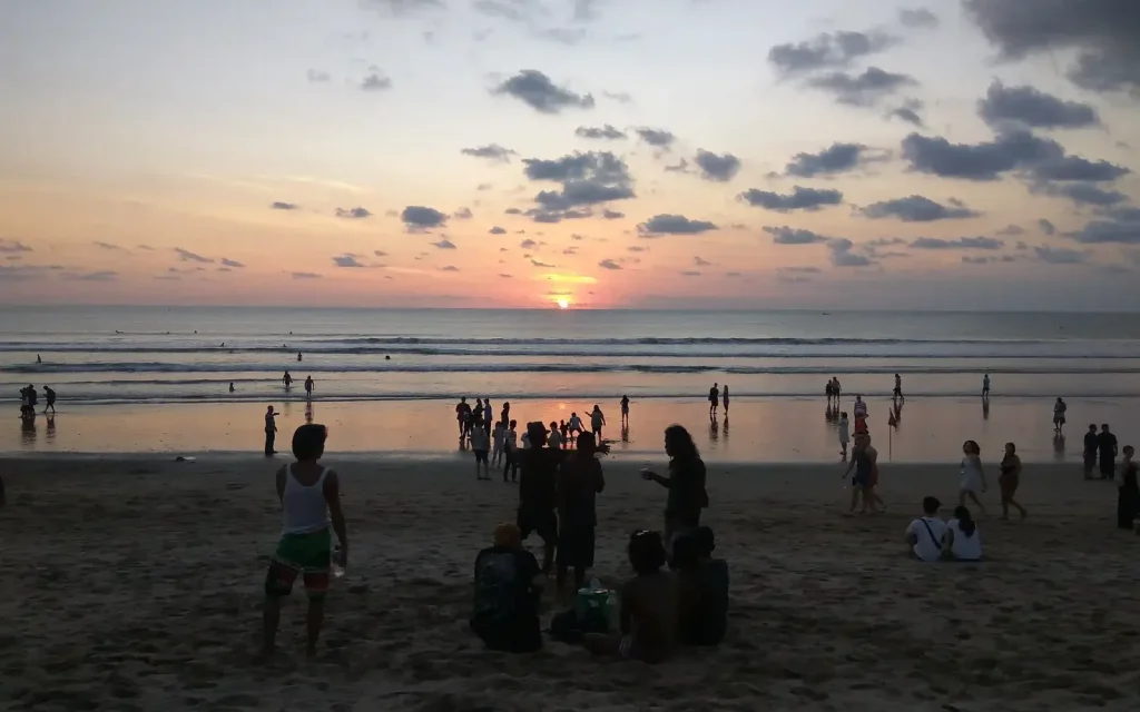 Sunset over Kuta Beach with people on the sand