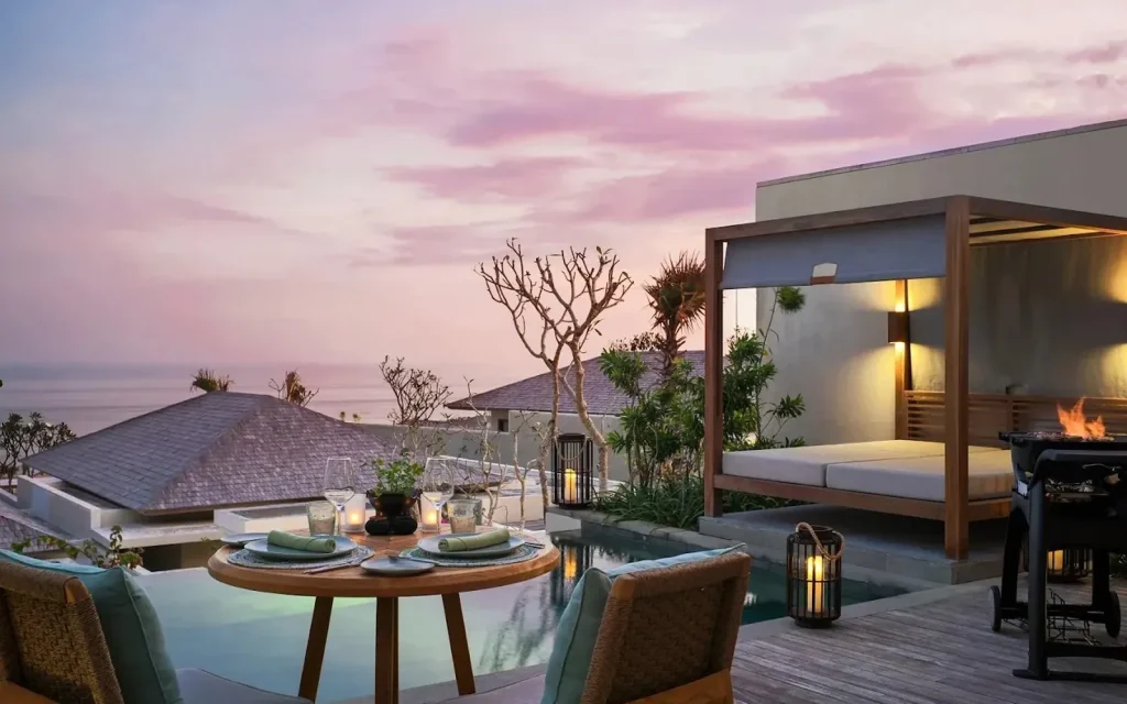 Villa terrace at dusk with a pool and daybed overlooking the sea in Uluwatu